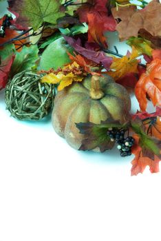 Autumn decorations include fake pumkins, berries and leaves, shot on a white background with copyspace at the bottom.