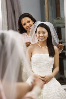 African-American friend holding Asian bride's veil.