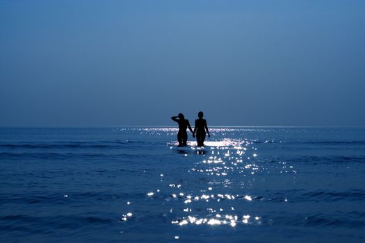 silhouette of two girls holding hands in the sea