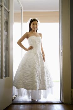 Portrait of an Asian bride standing in doorway.
