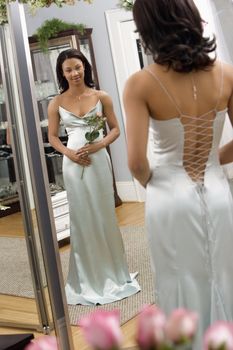 Portrait of an African-American woman in a elegant evening gown looking in mirror.