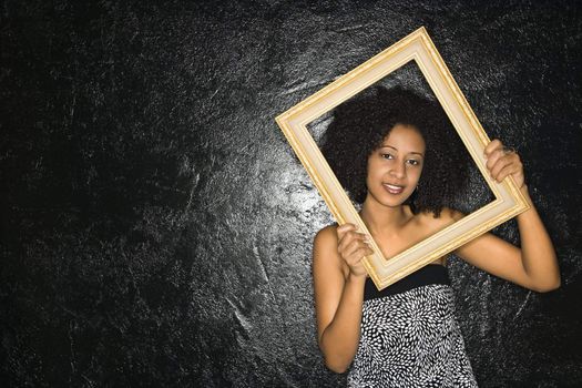 African-American woman holding frame over her face.