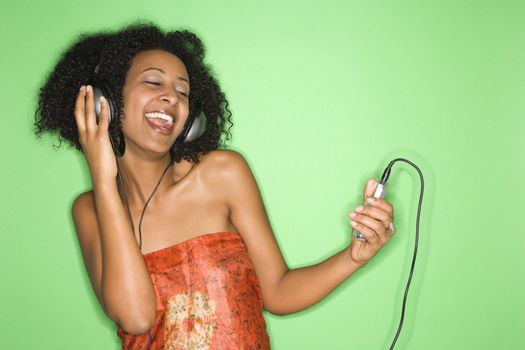 African-American woman listening to music through headphones.