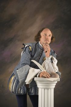 William Shakespeare in period clothing holding leaning on column with hand to chin in thoughtful expression.