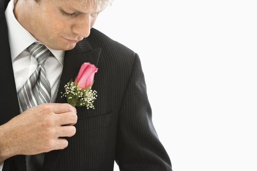 Caucasian groom adjusting boutonniere.