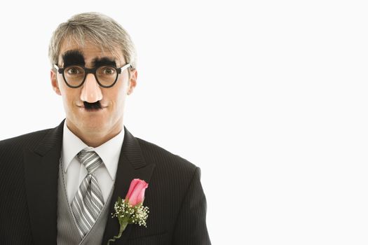 Caucasian groom wearing groucho glasses making eye contact.