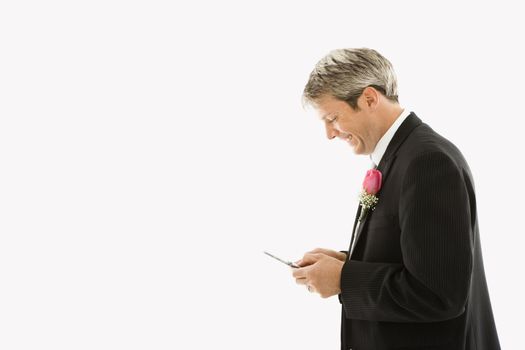 Caucasian groom texting on cellphone.