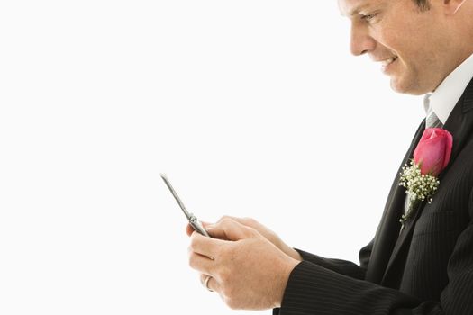 Caucasian groom texting on cellphone.