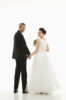 Portrait of Caucasian groom and Asian bride holding hands.