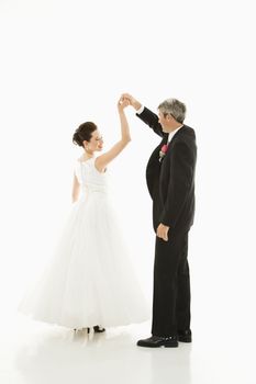 Portrait of Caucasian groom and Asian bride dancing.