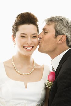 Portrait of Caucasian groom kissing Asian bride.