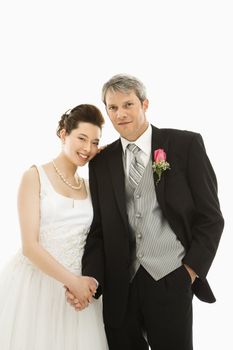 Portrait of Caucasian groom and Asian bride holding hands.