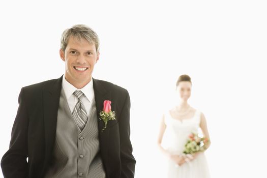 Caucasian groom in foreground and Asian bride in background.