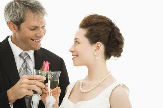 Caucasian groom and Asian bride toasting with champagne glasses.