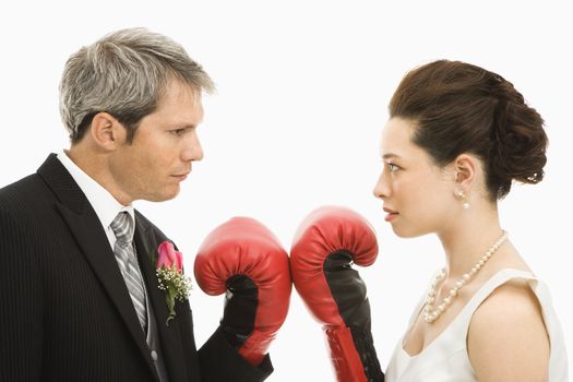 Caucasian groom and Asian bride wearing boxing gloves.