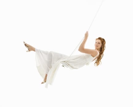 Caucasian bride swinging in swing set and looking at viewer.