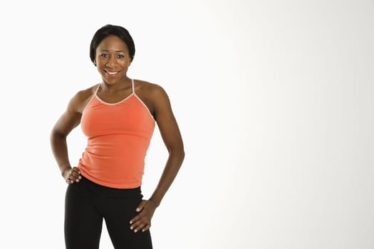 African American young adult woman in athletic wear smiling at viewer with hands on hips.