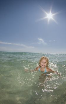 a young girl plays in the ocean on a calm bright sunny day