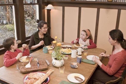 Family at breakfast table, two woman, boy and girl