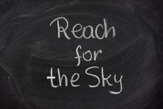 reach for the sky phrase handwritten with white chalk on blackboard