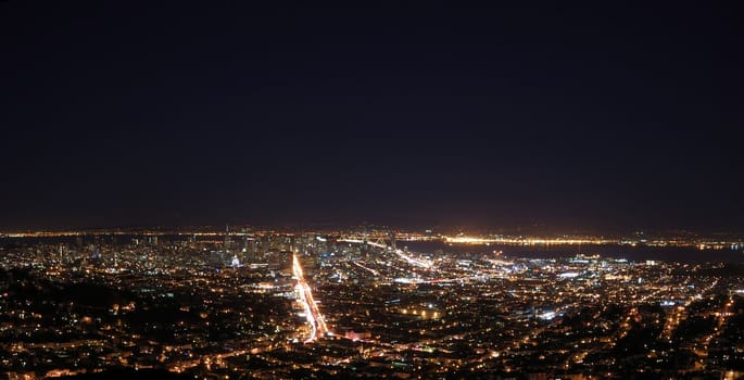 San Francisco at Night Panorama showing the Bay Bridge and downtown with Market Street as the brightest and Oakland across the Bay