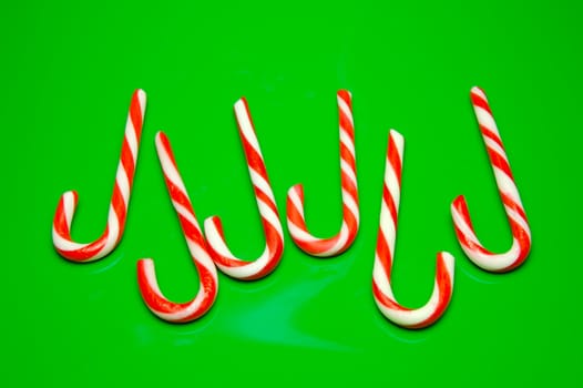 Christmas candy canes isolated against a green background