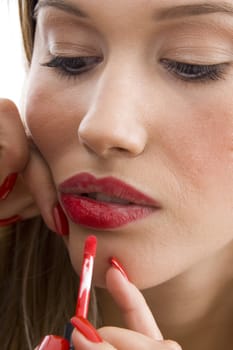 gorgeous woman applying red lipstick on an isolated white background