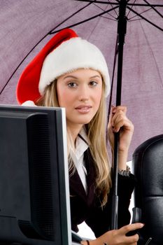 professional woman wearing christmas hat and holding umbrella in office