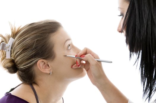 model getting eye makeup from beautician against white background