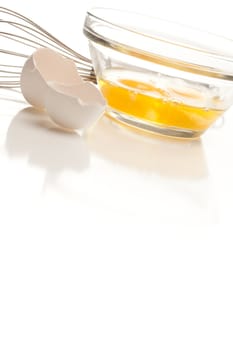 Hand Mixer with Eggs in a Glass Bowl on a Reflective White Background.