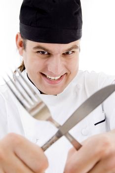 close up of young chef holding fork and knife crossed with white background