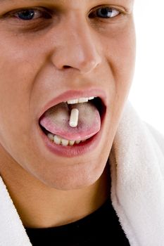 young man putting pill on his tongue against white background