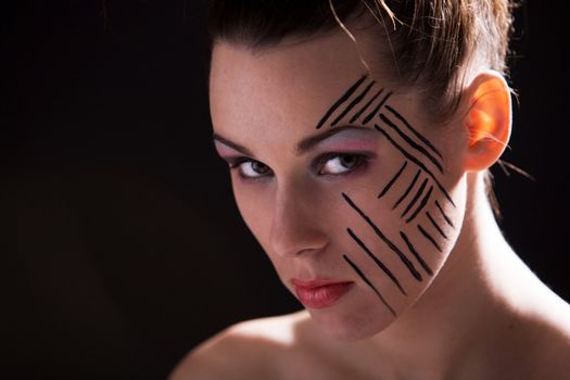 Beautiful woman with striped makeup on dark background