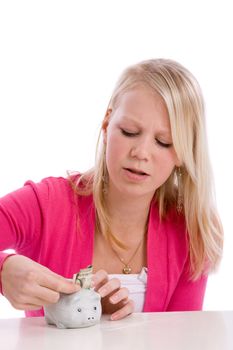 Pretty teen trying to put a dollar into a very small piggybank