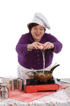 Chef breaking an egg in her pan on white background