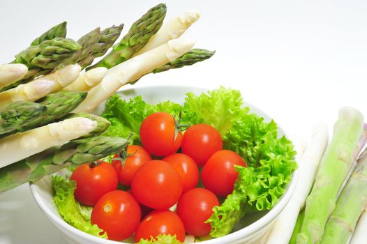 Cherry tomatoes in a bowl with asparagus on the side