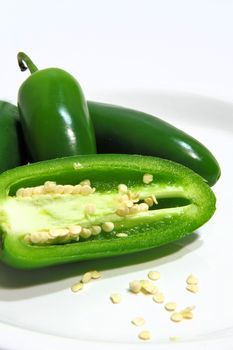 Sliced and whole chili peppers with seeds exposed on a white saucer