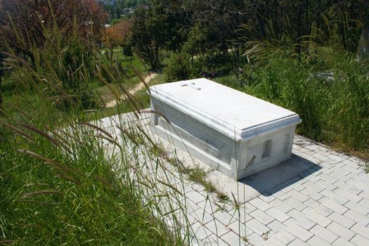 old marble christian grave among grass