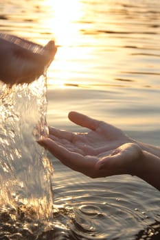 woman hands giving you water on sunset