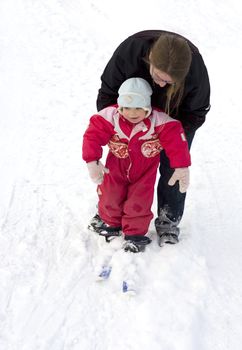 Mother teaching small child cross country skiing