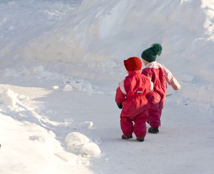 Children in thick winter clothes walking down a snowy road