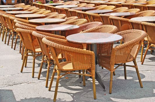 restaurant street terrace with wicker chairs and round tables