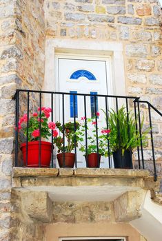 Entrance door of old stone house with flowerpots in Budva