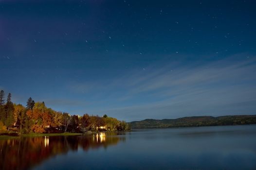 a calm lake at night with stars in the sky