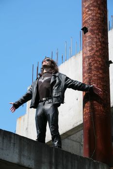 man in black leather cloth amongst iron-concrete construction