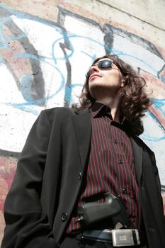 portrait of the young man with gun in black sunglasses in gangster style