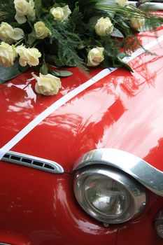 A bouquet of white roses on a vintage car which is used in a wedding