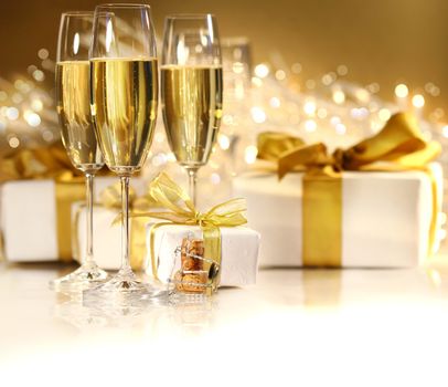 Glasses of champagne with gold ribboned gifts 