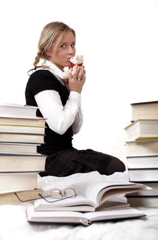 Schoolgirl or student kisses teddy-bear. Around her lie books. Isolated on white 