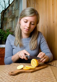 pretty woman cuts lemon in kitchen